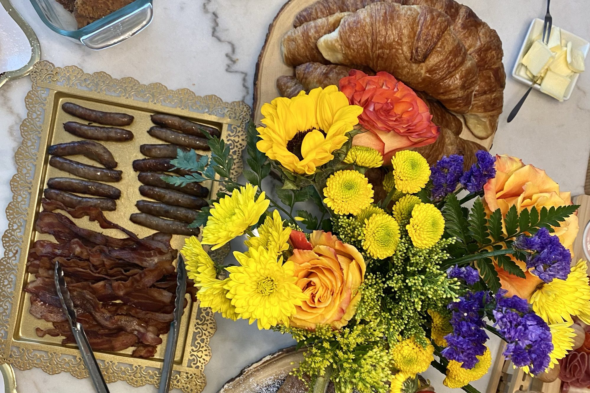 An overhead BlendedSoul catering spread of pastries, fruit and fresh flowers