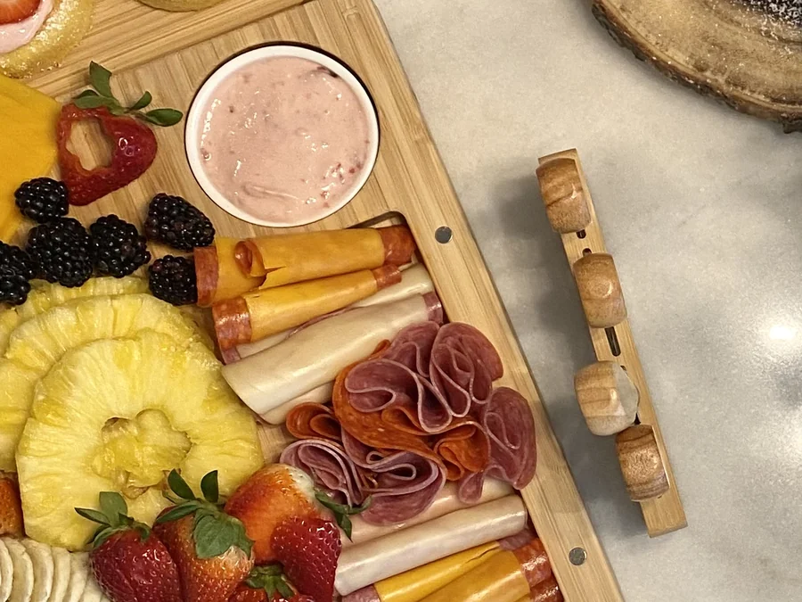 A charcuterie board of cured meats, cheeses, crackers and fruit