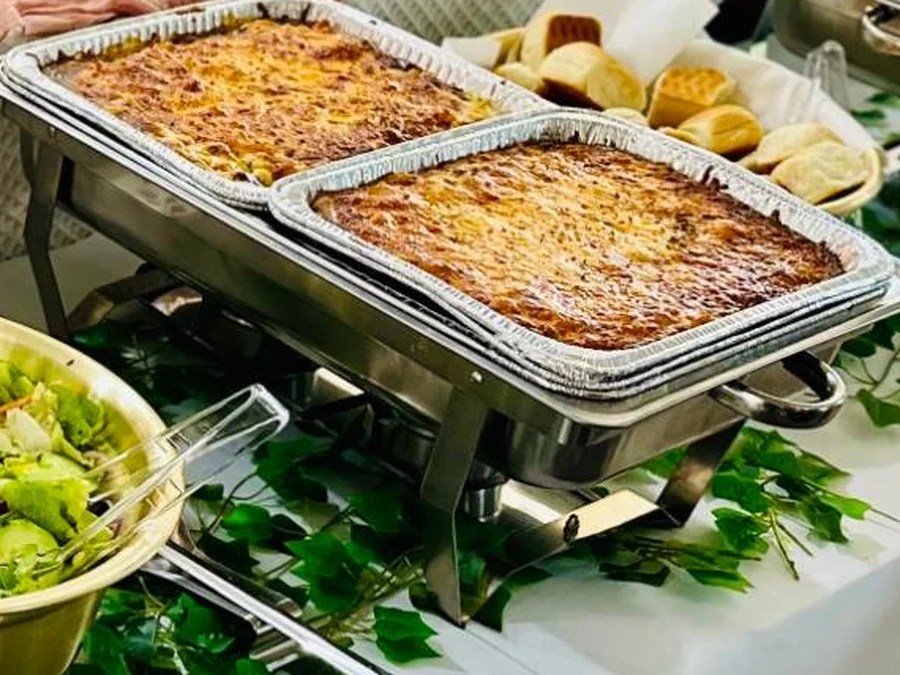 Two pans of baked macaroni and cheese with yeast rolls